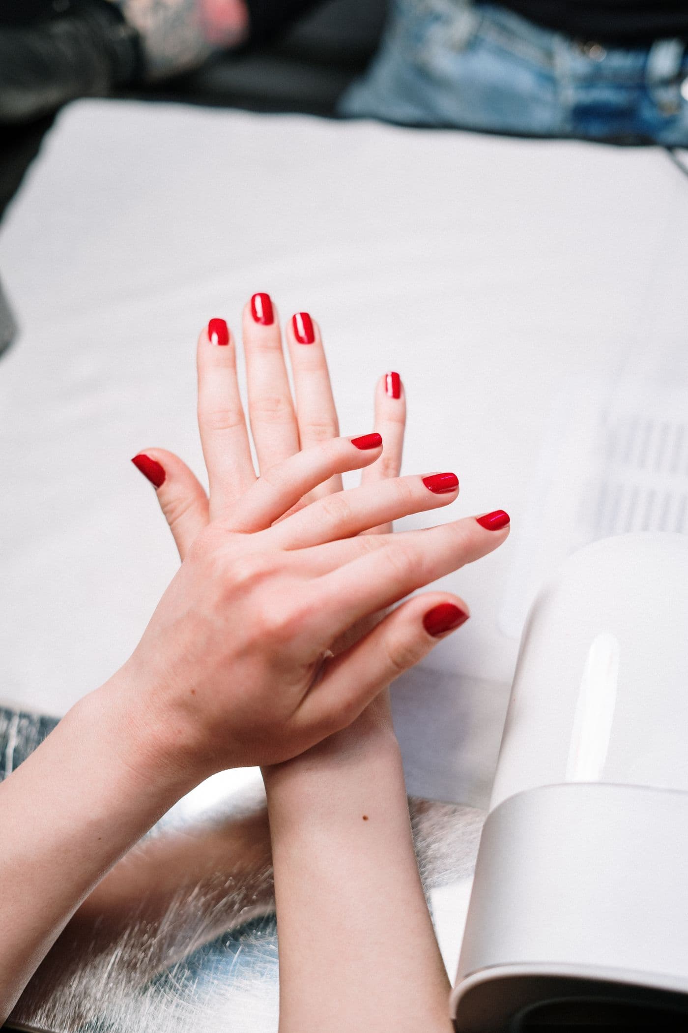 Mãos com esmaltação vermelha durante atendimento de manicure